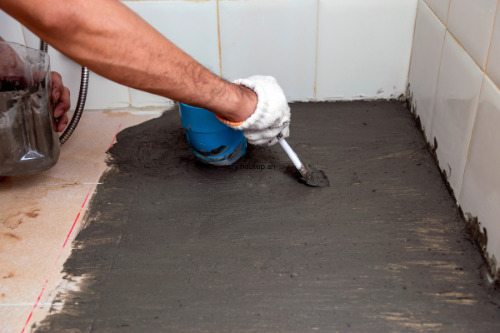 Waterproofing treatment being applied to bathroom floor